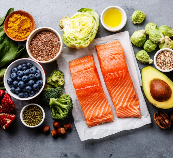 Top-10-anti-inflammatory-foods-ff69255 Selección de alimentos saludables para una alimentación limpia: pescado, frutas, verduras, semillas, superalimentos, cereales, verduras de hoja sobre fondo de hormigón gris, espacio de copia